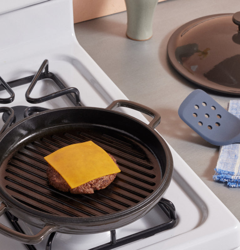 black cast iron hot grill with cheeseburger on hob