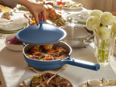 Blue frying pan with food on a table set for a meal