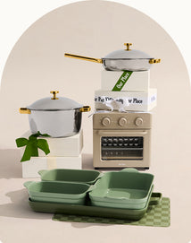 Set of green cookware with a small oven and decorative elements on a neutral background