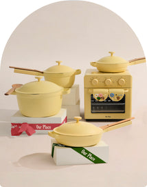 Set of yellow cookware including pots and a small stove on a light background