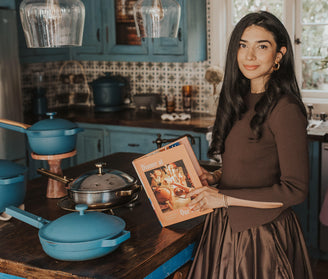 our place shiza shahid in kitchen with blue cookware and our place cookbook
