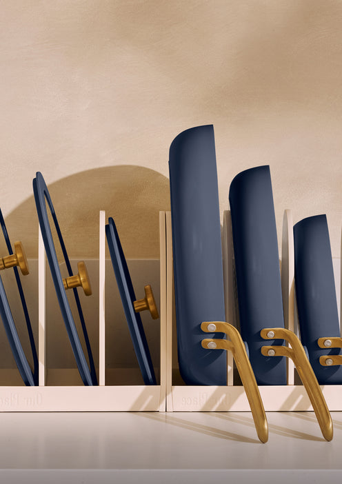 Set of blue hairbrushes in a white holder with gold accents on a beige background