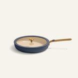 Blue frying pan with gold handle and lid on a white background