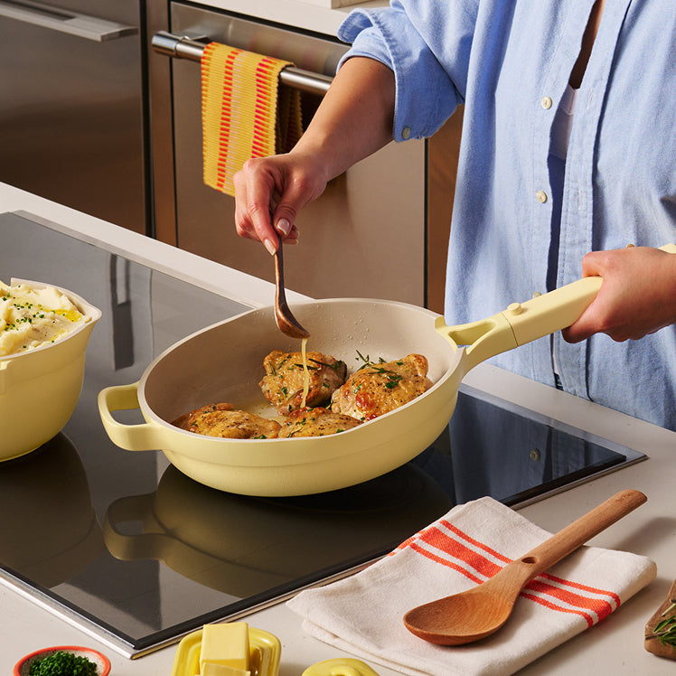 Person cooking in a kitchen with a yellow frying pan on a stove.
