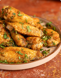 A plate of seasoned chicken wings garnished with fresh herbs.