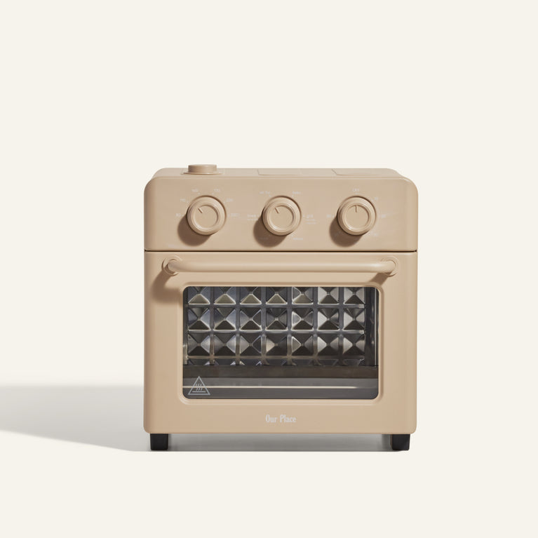 A beige countertop toaster oven with three control knobs and a glass door, featuring a diamond-patterned interior.
