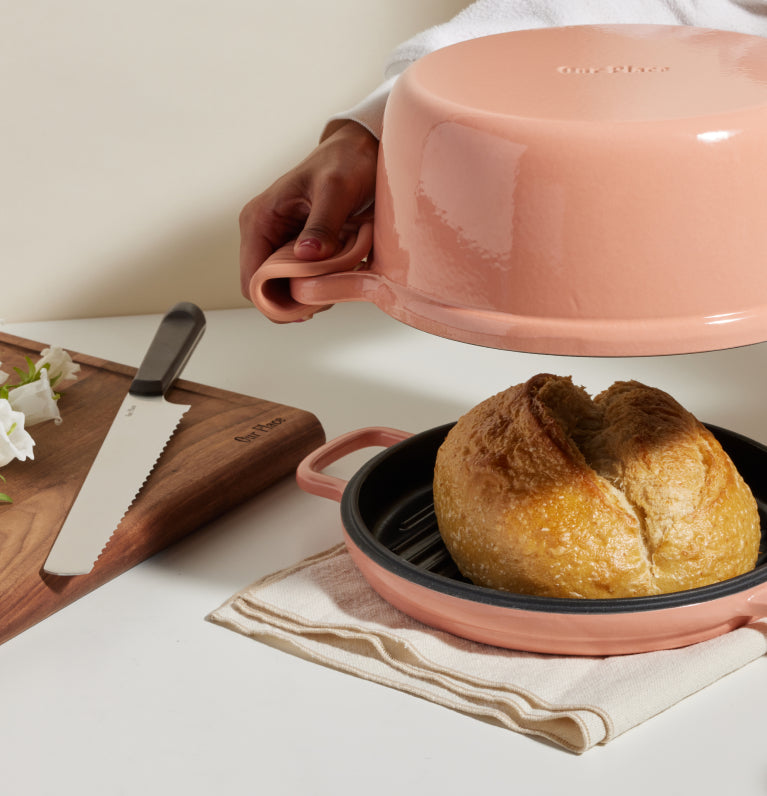 pink cast iron perfect pot and hot grill with loaf of bread and walnut cutting board