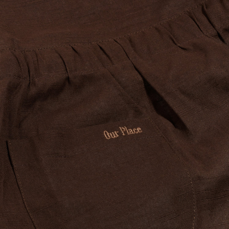 Our Place logo embroidered on the pocket of a black Hosting Apron