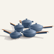 The Cookware Set+ includes five blue ceramic nonstick pieces with matching lids and wooden handles, arranged on a white background to highlight their stylish design and functionality.