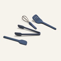 Five sturdy blue Mini Utensil Essentials—spatula, tongs, whisk, slotted turner, and spoon—are displayed on a light background.