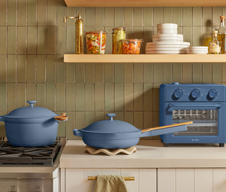 Blue cookware set on a kitchen counter with a tiled wall and shelves in the background.
