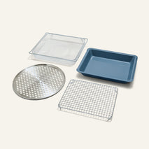 The Wonder Oven Pro Chef’s Kit includes a blue rectangular baking pan, mesh tray, round perforated tray, and wire cooling rack on a plain light background.