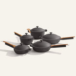 The Cookware Set+ features five black nonstick pieces with wooden handles and lids, including saucepans, sauté pans, and a wooden spoon—ideal for starting your ceramic cookware collection.