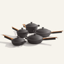The Cookware Set+ features five black nonstick pieces with wooden handles and lids, including saucepans, sauté pans, and a wooden spoon—ideal for starting your ceramic cookware collection.
