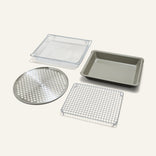 The Wonder Oven Pro Chef’s Kit features a perforated round tray, square wire rack, rectangular mesh basket, and baking pan on a plain background.