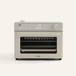 The Wonder Oven Pro is a beige countertop oven with a digital display, control knobs, and a glass door revealing interior racks.