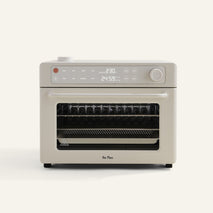 The Wonder Oven Pro is a beige countertop oven with a digital display, control knobs, and a glass door revealing interior racks.
