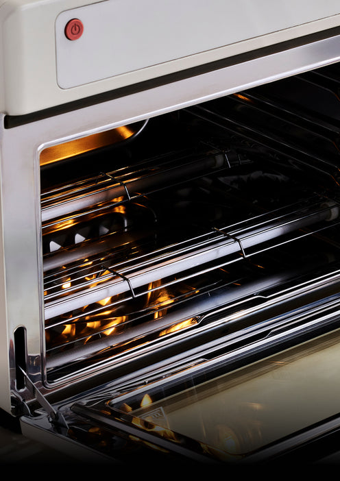 An open oven interior showing wire racks and a red power button on the upper front panel.