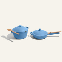 Blue cookware set with wooden handles on a light gray background