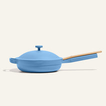The Always Pan 2.0, a bestselling light blue nonstick frying pan with lid and wooden handle, is displayed against a plain off-white background.
