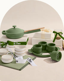 Green ceramic kitchenware set with 'Our Place' branding on a neutral background