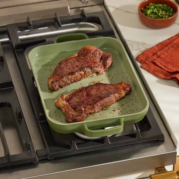 Steak cooking on a green Mini Griddle Pan on the stove