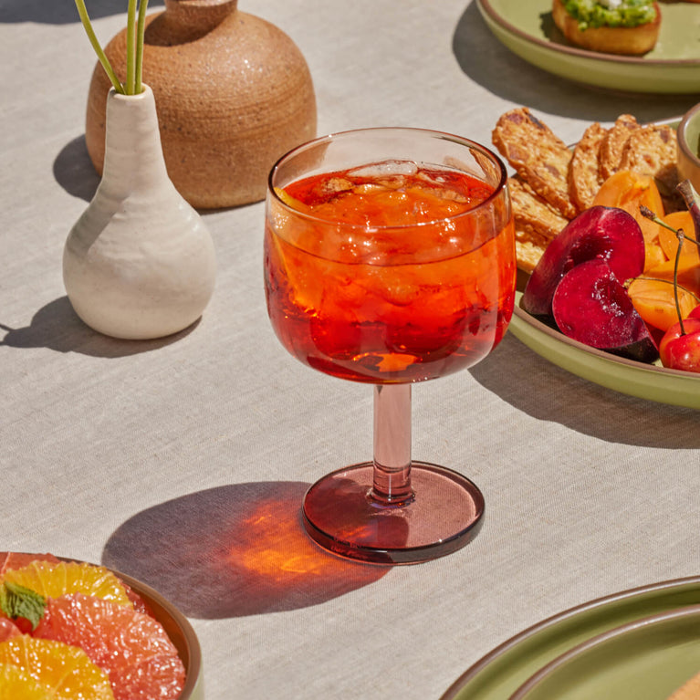 Orange and pink Party Coupe filled with an orange drink on a table