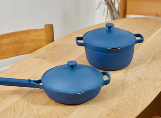 Two blue cookware items on a wooden table with a neutral background