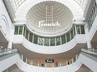 Interior of a shopping mall with 'Fenwick' branding on the ceiling.