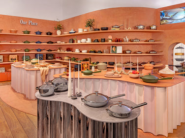 Display of kitchenware including pots, pans, and bowls in a store setting.