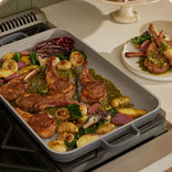 black griddle pan on stove searing meat and vegetables