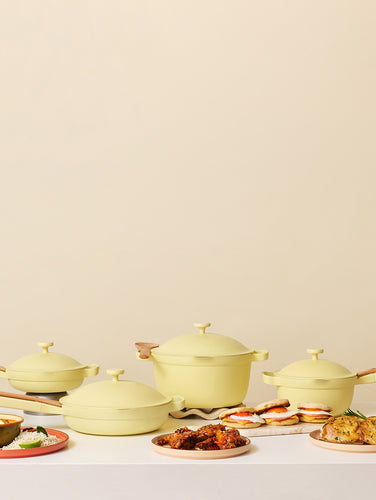 Set of yellow cookware with food on a beige background