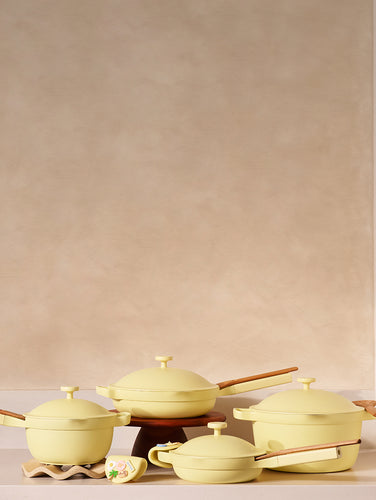 Set of yellow ceramic cookware on a beige surface