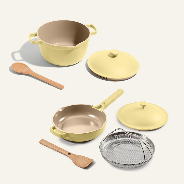 Set of yellow cookware including pots, pans, and utensils on a white background
