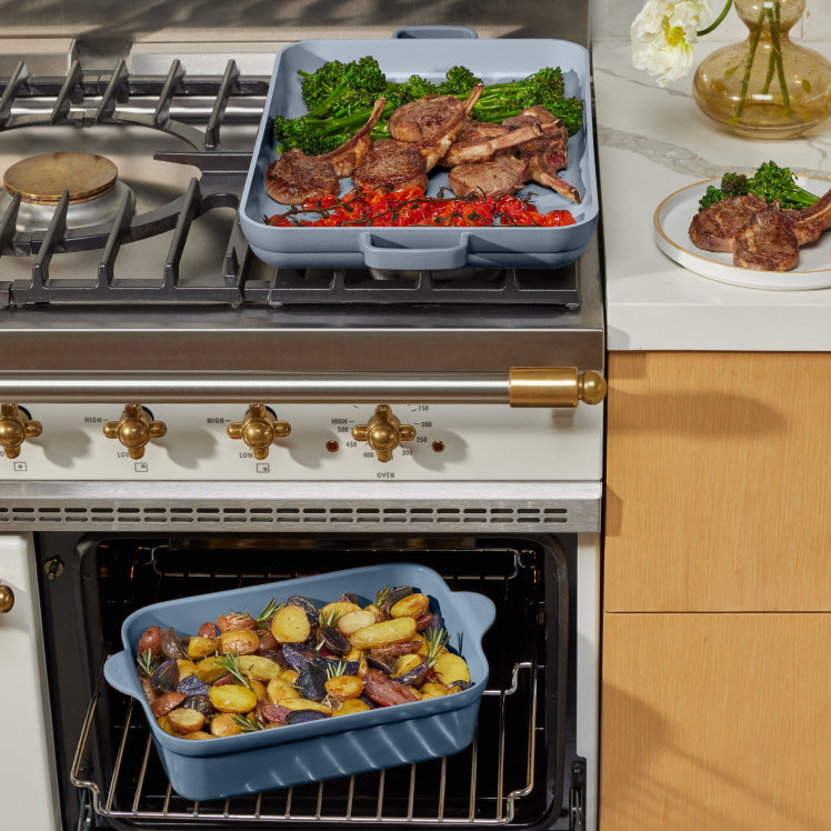 blue griddle pan on stove cooking meat and vegetables, blue aluminum baker on oven cooking potatoes