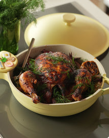 Roasted chicken in a yellow ceramic dish on a kitchen counter