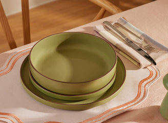 green dinner bowls, salad plates and dinner plates stacked on table