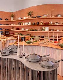 Display of cookware and kitchen items in a store setting with shelves and countertop.