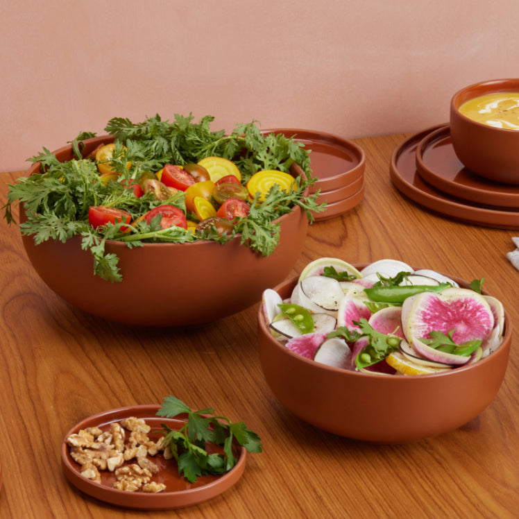 red serving bowls with salad and dinnerware on table