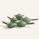 The Cookware Set+ features four green nonstick pots and pans with matching lids and wooden handles, all arranged on a plain light background.