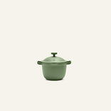 The Petite Perfect Pot, a matte green nonstick pot with two handles and a fitted lid, ideal for personal servings, is centered against a plain off-white background.