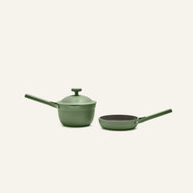 The Tiny Cookware Duo, featuring a green saucepan with lid and a matching green frying pan, is displayed side by side on a simple light background.