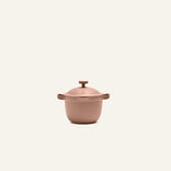 The Petite Perfect Pot, a matte rose-colored nonstick pot with side handles and matching lid ideal for personal servings, is centered on a plain off-white background.