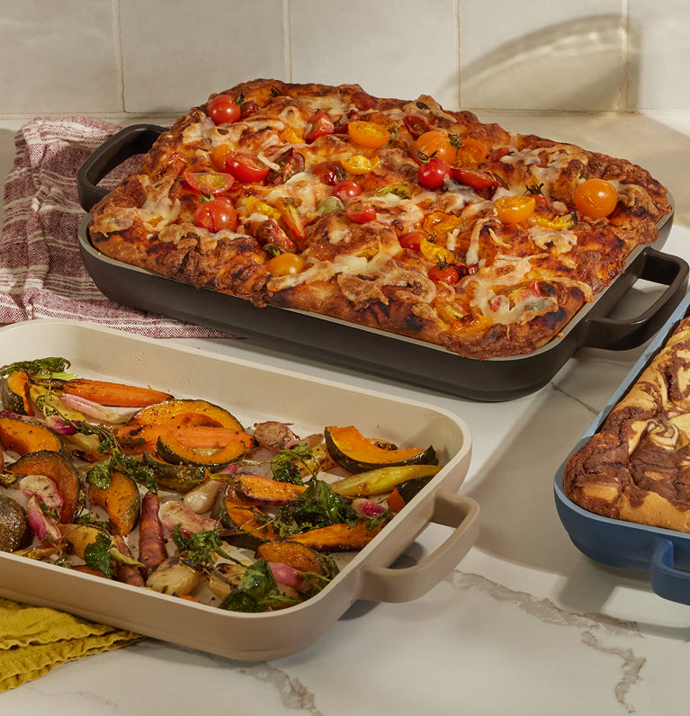 Three baked dishes on a kitchen counter with a tiled wall background