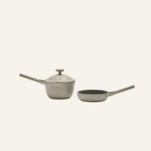 The Tiny Cookware Duo, featuring a beige saucepan with lid and matching frying pan—both with long handles—are displayed side by side on a light background.