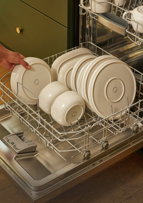 A variety of white dinnerware stacked in the dishwasher